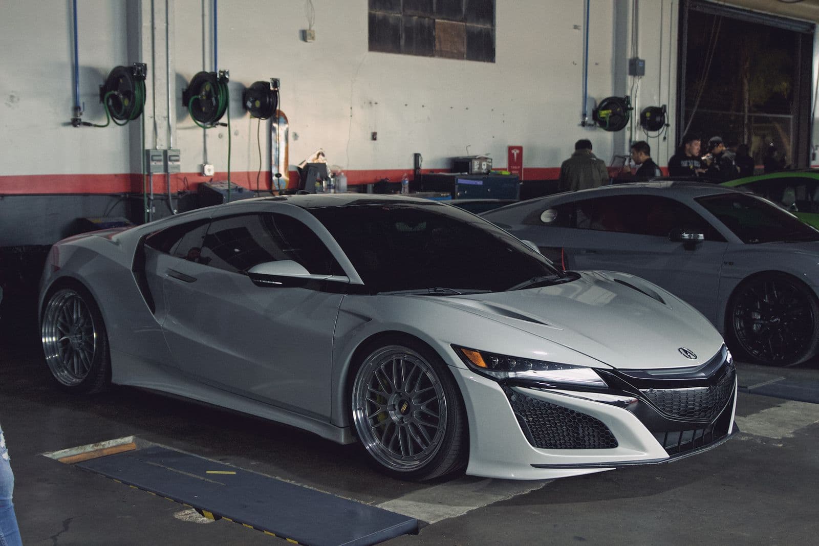 Silver sports car parked on a dark floor in a show garage setting — a finish example